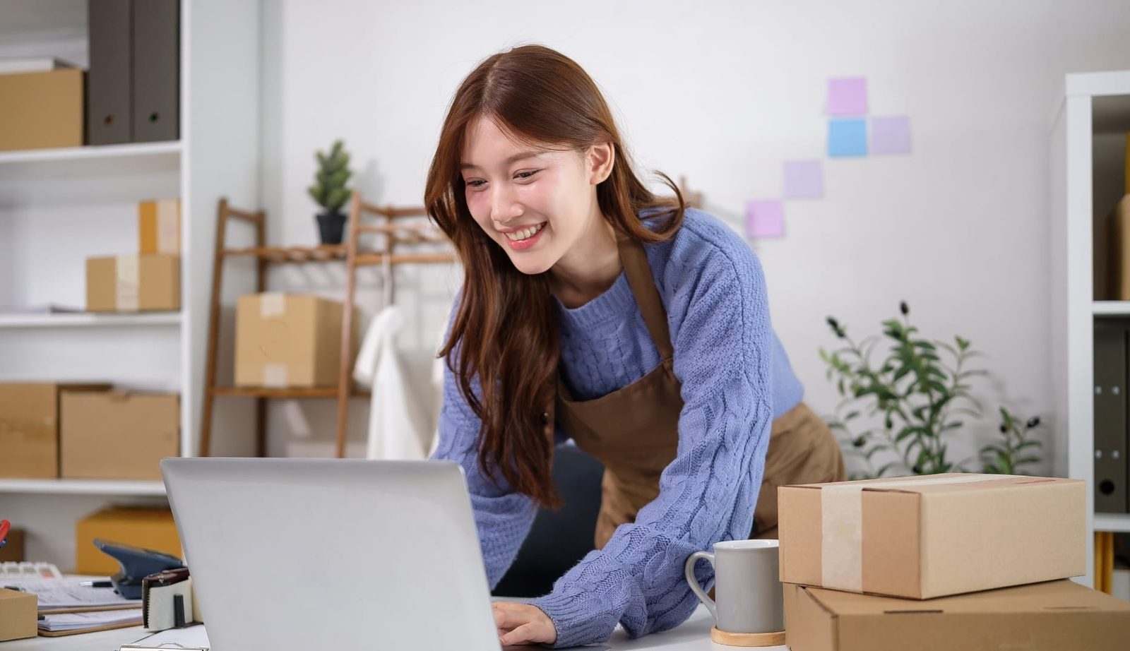 Pemilik usaha tersenyum melihat pesanan masuk di laptop